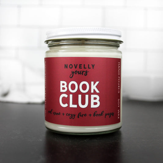 scented soy wax candle called book club on red wine label in clear jar with white lid
