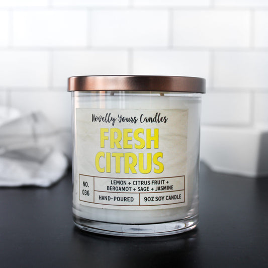 fresh citrus soy wax candle with yellow text in clear glass tumbler with bronze lid.