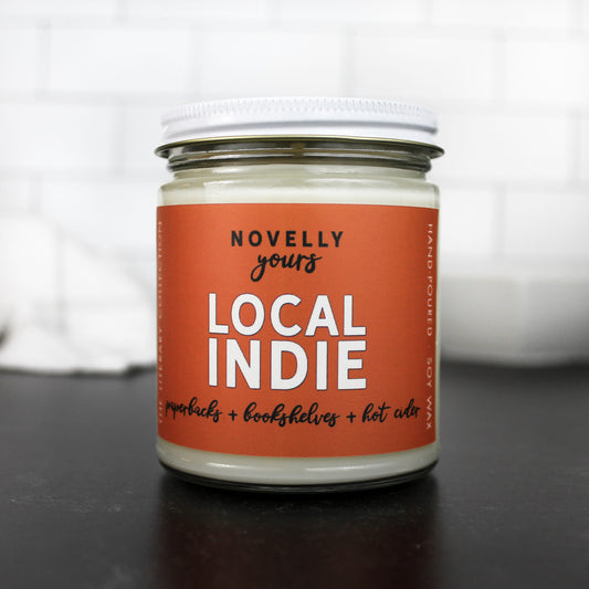 Local indie scented soy wax candle with burnt orange label in clear glass jar with white lid