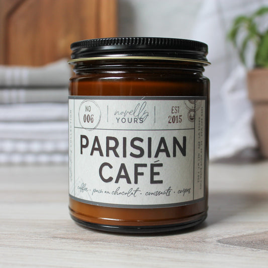 scented soy wax candle in amber jar with black lid reading "Parisian cafe"