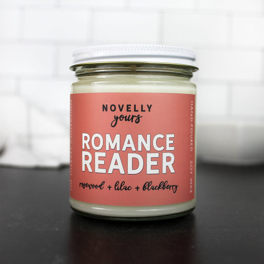 romance reader scented soy wax candle in clear glass jar with white lid and soft rose colored label