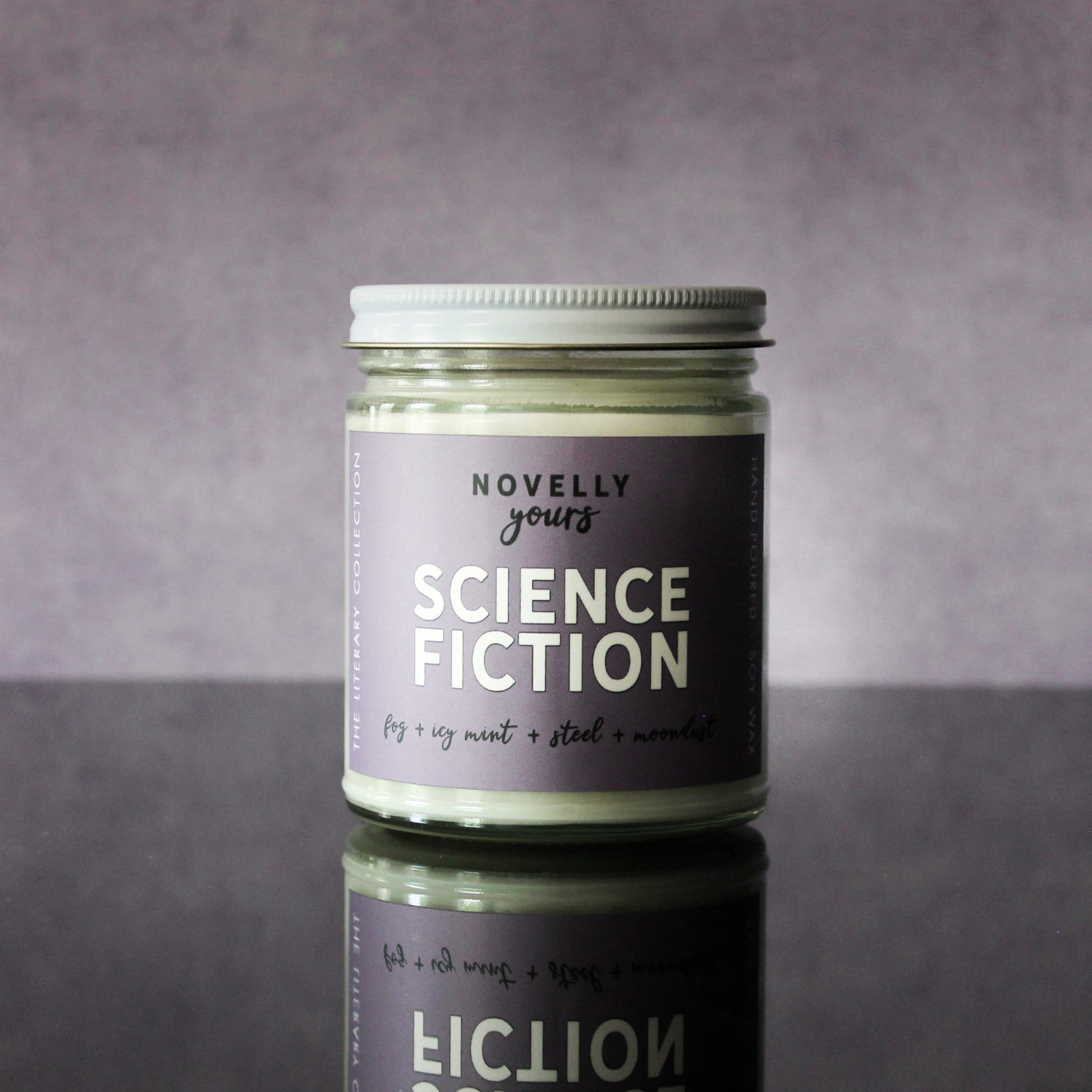 scented soy wax candle labeled "Science Fiction" sitting against a purple background on a black reflective base