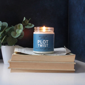 plot twist scented soy wax candle in clear glass jar with white lid and blue label, book candle for readers