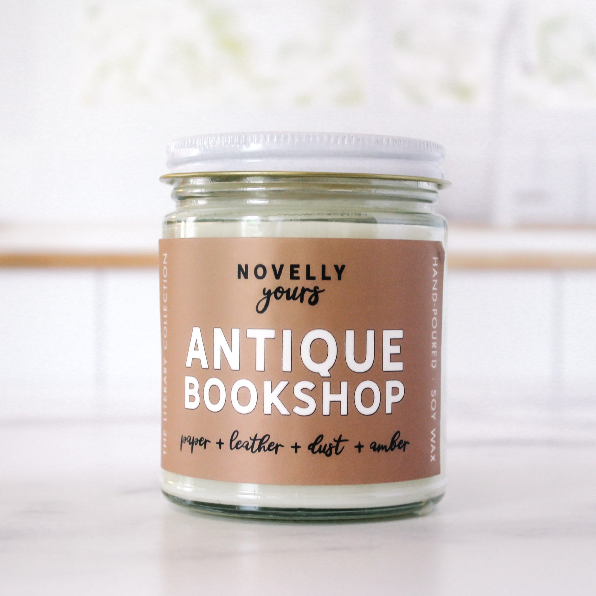 book inspired candle "Antique Bookshop" with beige label sits in front of kitchen background