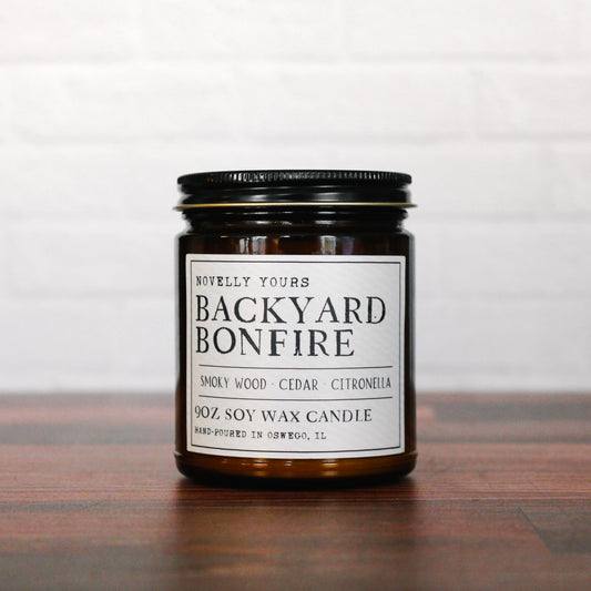 backyard bonfire soy wax candle in amber jar with black lid, campfire scented candle