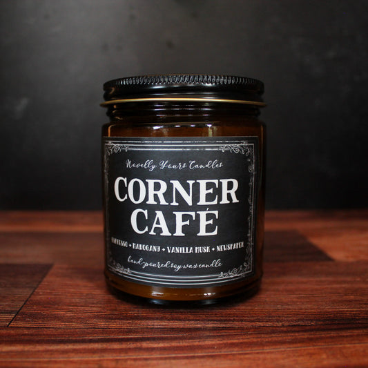 corner cafe scented soy wax candle in amber jar with black lid on wooden and black background