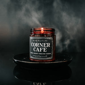 corner cafe scented soy wax candle in amber jar, lit on black tray against black background