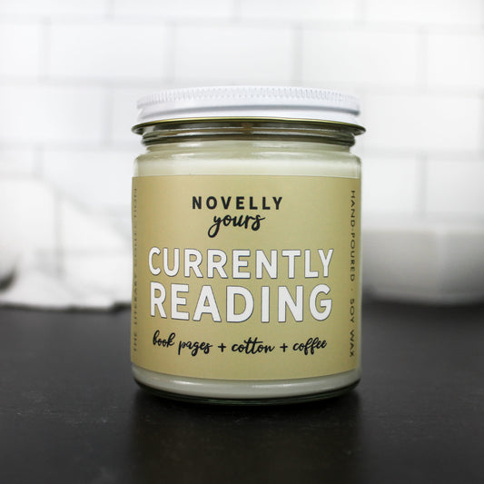 scented soy wax candle featuring "currently reading" title on a tan label with a white metal lid