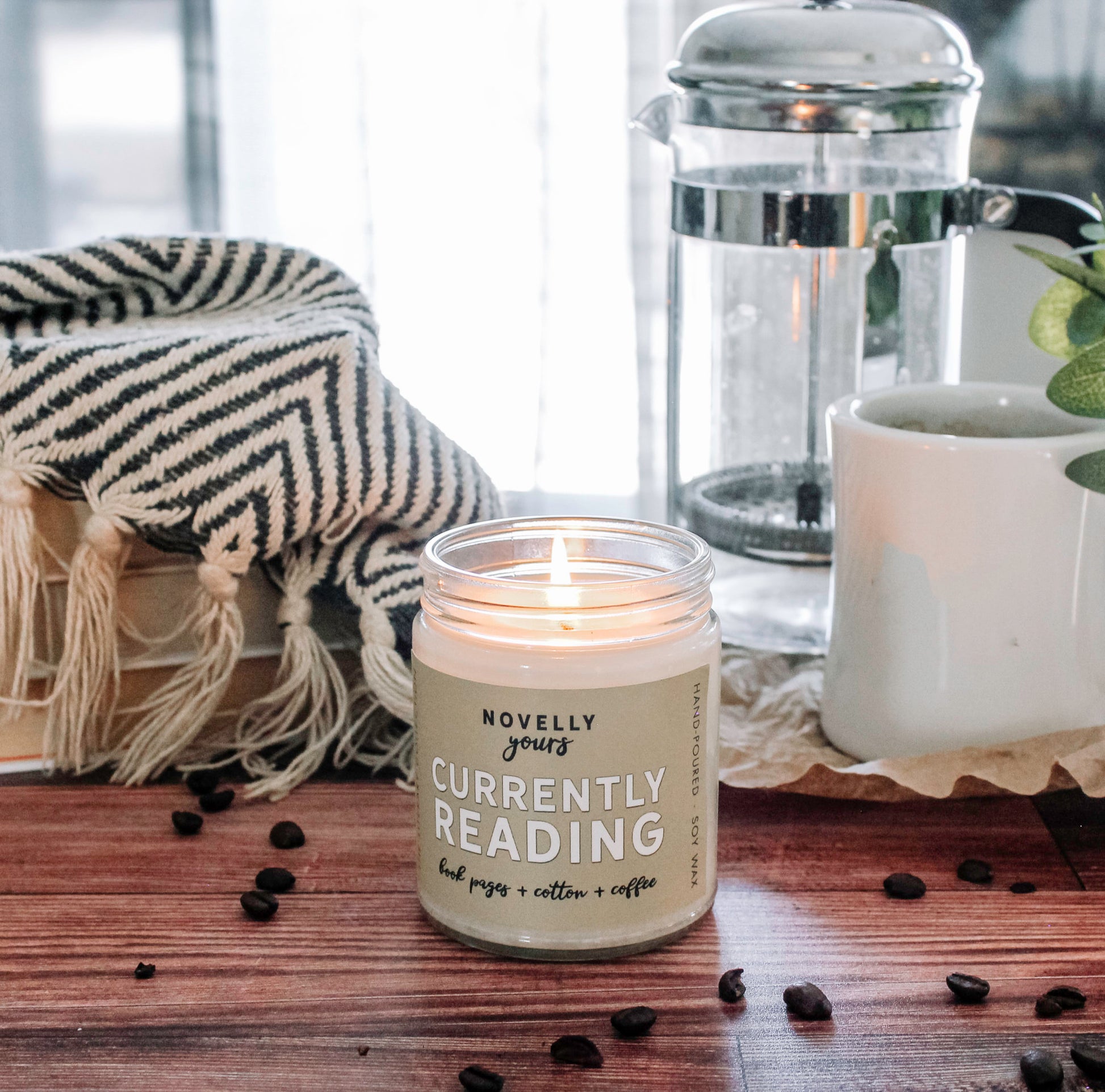 scented soy wax candle featuring "currently reading" title on a tan label on a decorative background