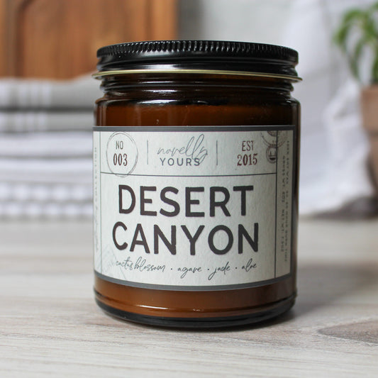 desert canyon scented soy wax candle in amber jar, on wooden surface in front of kitchen items