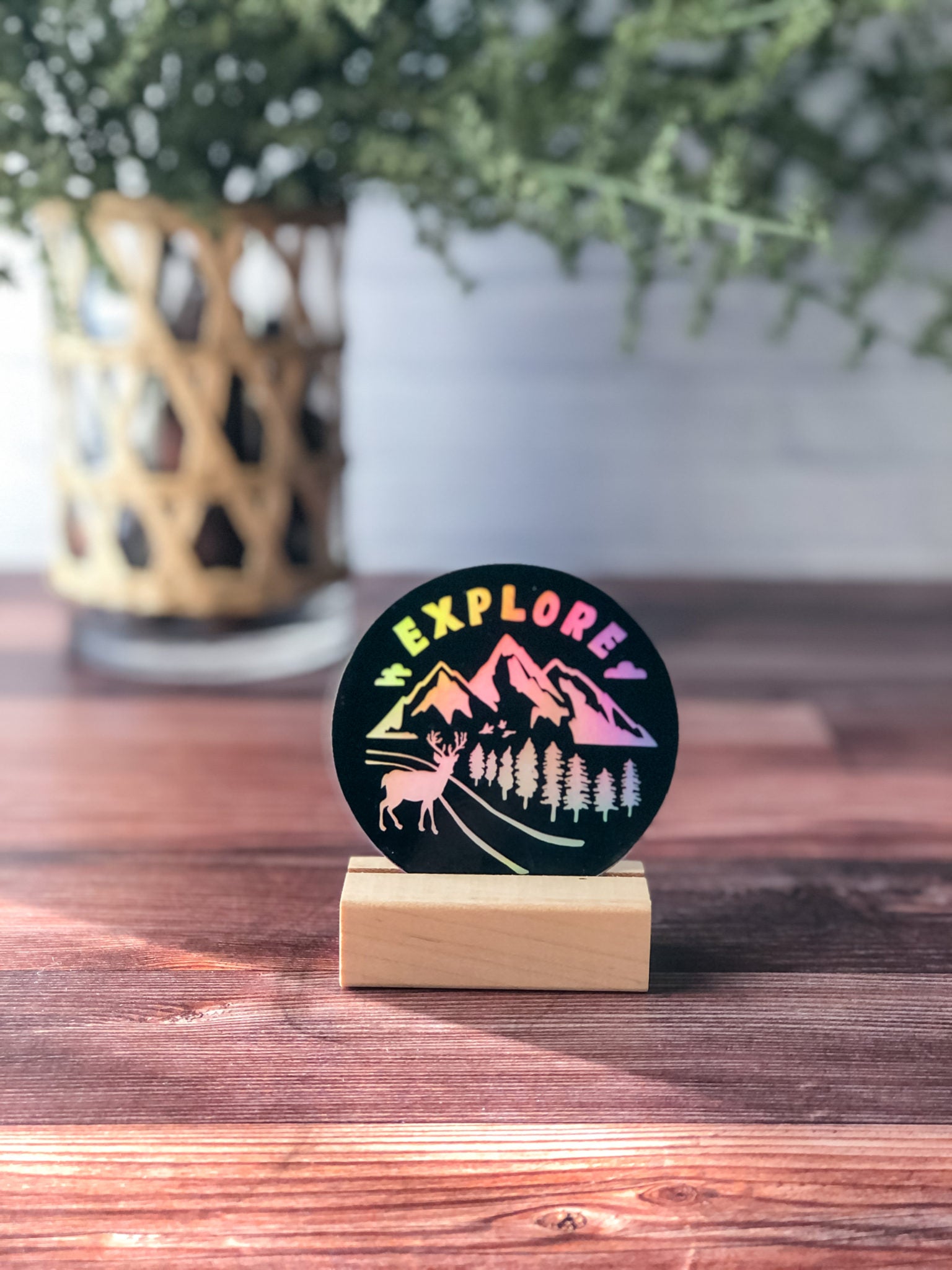 holographic sticker with word "explore" and nature designs of mountains, pine trees, and deer