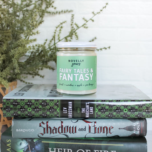 fairy tales & fantasy candle in green label with white lid on a stack of green hued fantasy books