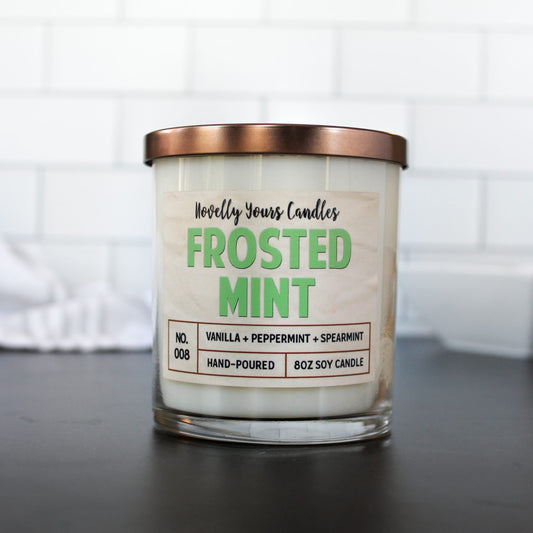 frosted mint candle with green text in clear glass jar with bronze lid