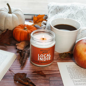 Local indie scented soy wax candle with burnt orange label in clear glass jar with white lid