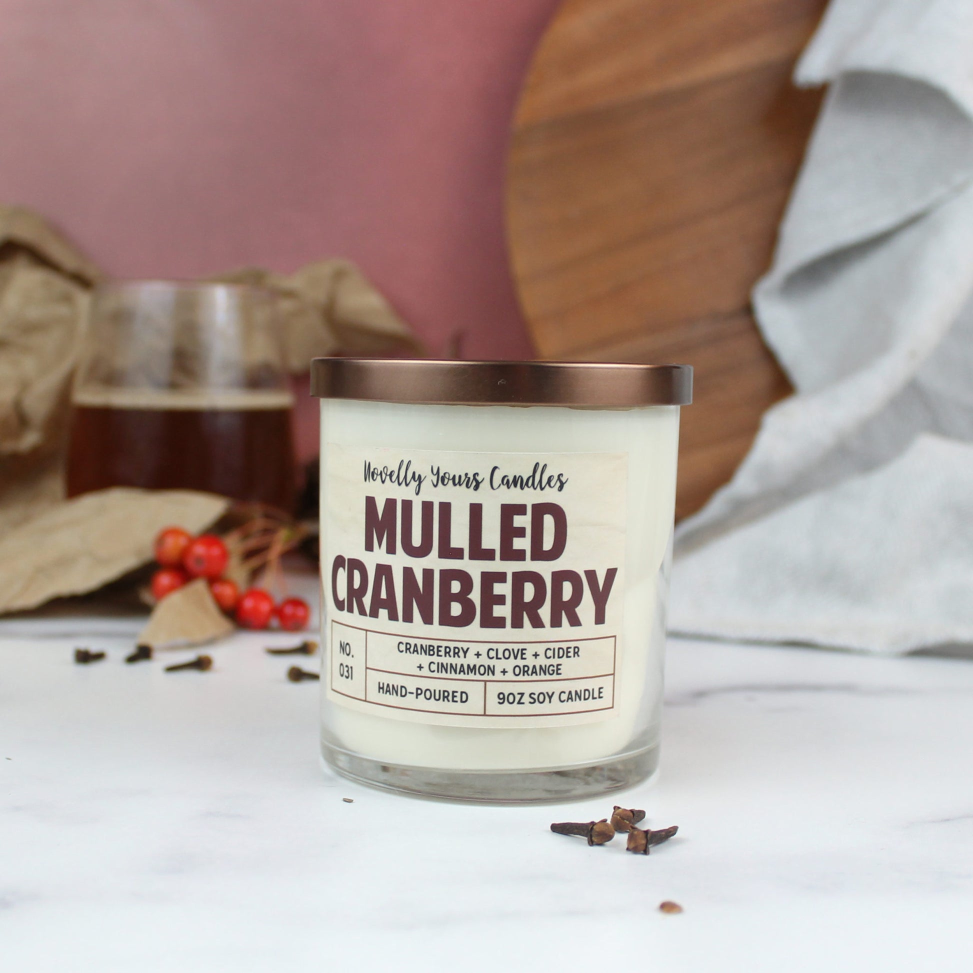 mulled cranberry scented soy wax candle in clear glass tumbler with bronze lid with decorative berries and clove
