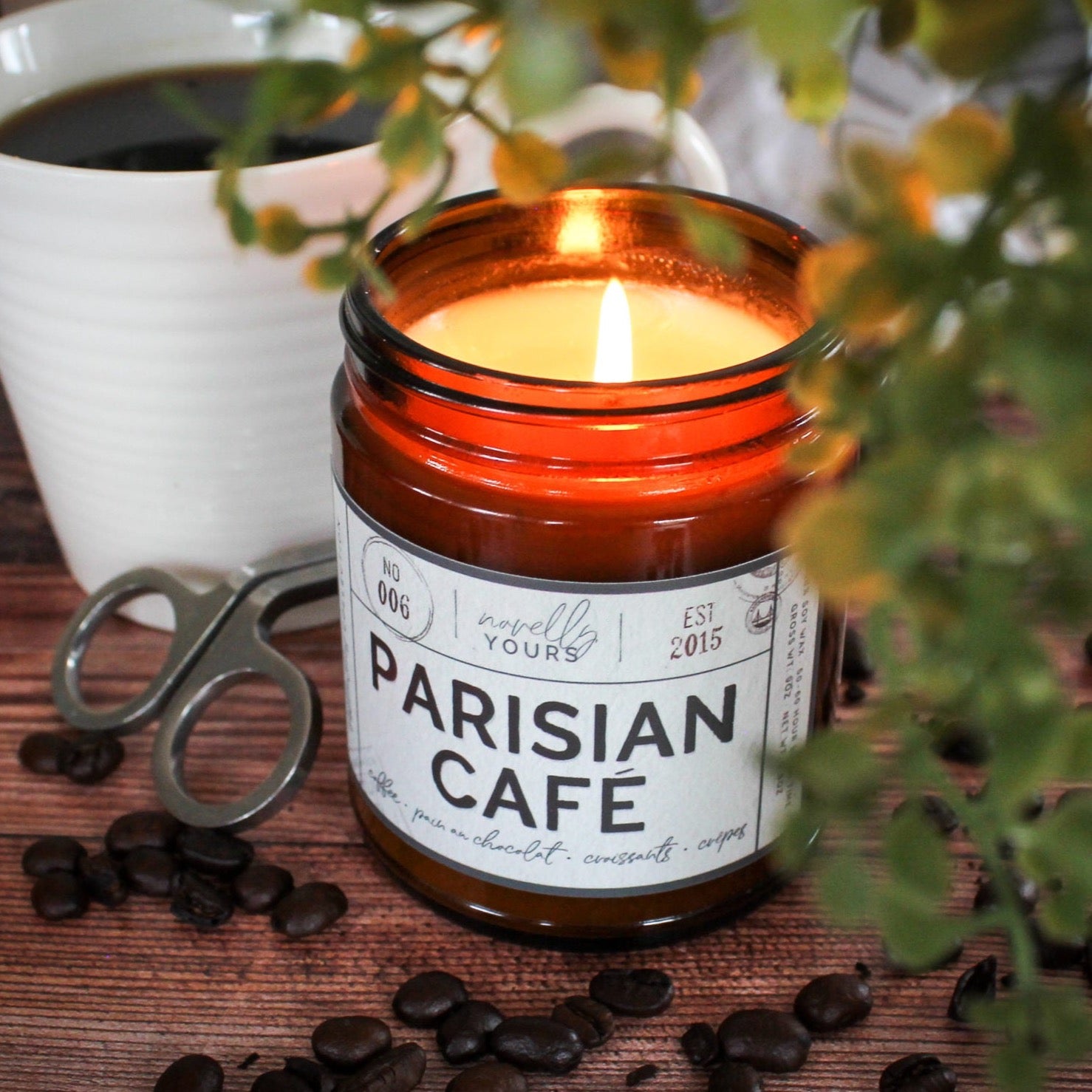 scented soy wax candle in amber jar, lit, surrounded by coffee beans reading "Parisian cafe"