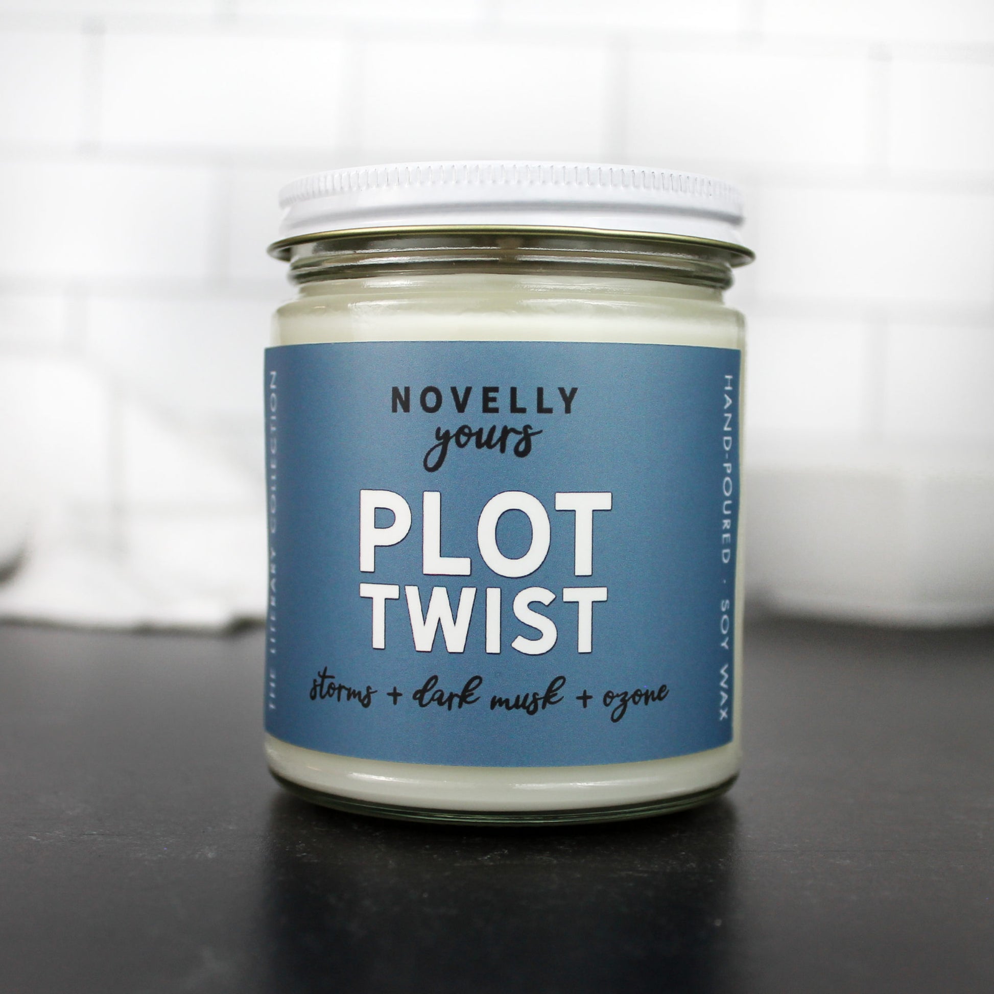 plot twist scented soy wax candle in clear glass jar with white lid and blue label