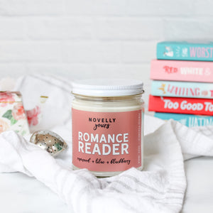 romance reader scented soy wax candle in clear glass jar with white lid and soft rose colored label