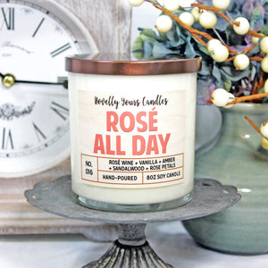 Rosé All Day scented soy wax candle in glass tumbler jar with bronze lid and pink label lettering