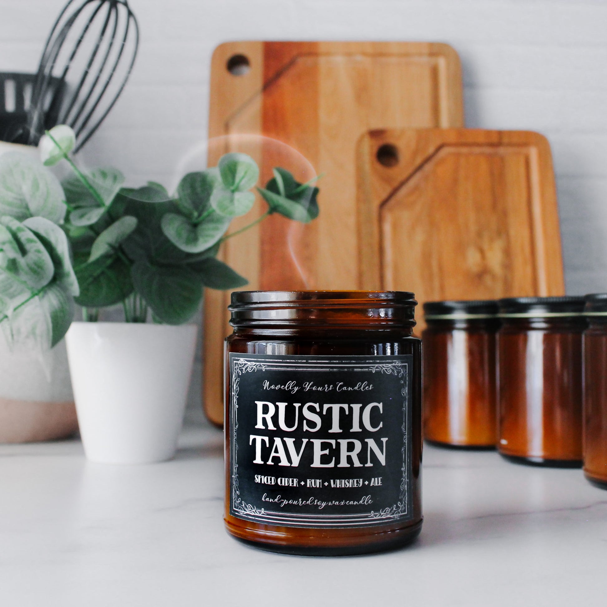 rustic tavern scented soy wax candle in amber jar with black label, smoke trailing out of top of extinguished candle