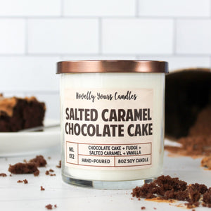 Salted Caramel Chocolate Cake scented soy wax candle in glass tumbler with bronze lid, surrounded by cake and baking implements
