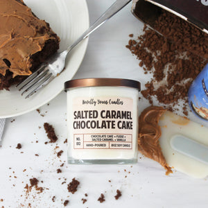 Salted Caramel Chocolate Cake scented soy wax candle in glass tumbler with bronze lid, surrounded by cake and baking implements