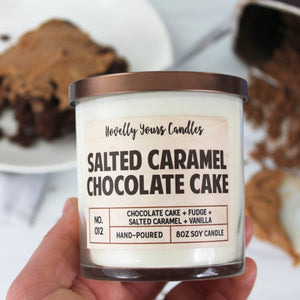 Salted Caramel Chocolate Cake scented soy wax candle in glass tumbler with bronze lid, surrounded by cake and baking implements