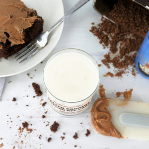 Salted Caramel Chocolate Cake scented soy wax candle in glass tumbler with bronze lid, surrounded by cake and baking implements (top view)