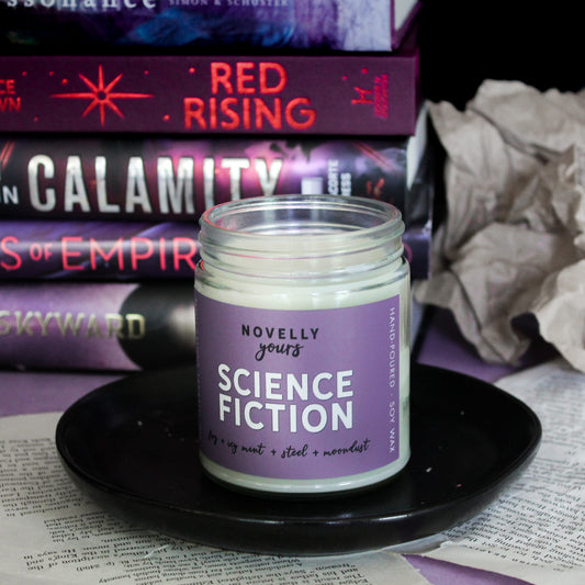 scented soy wax candle labeled "Science Fiction" sitting on on a black saucer in front of a stack of sci-fi books